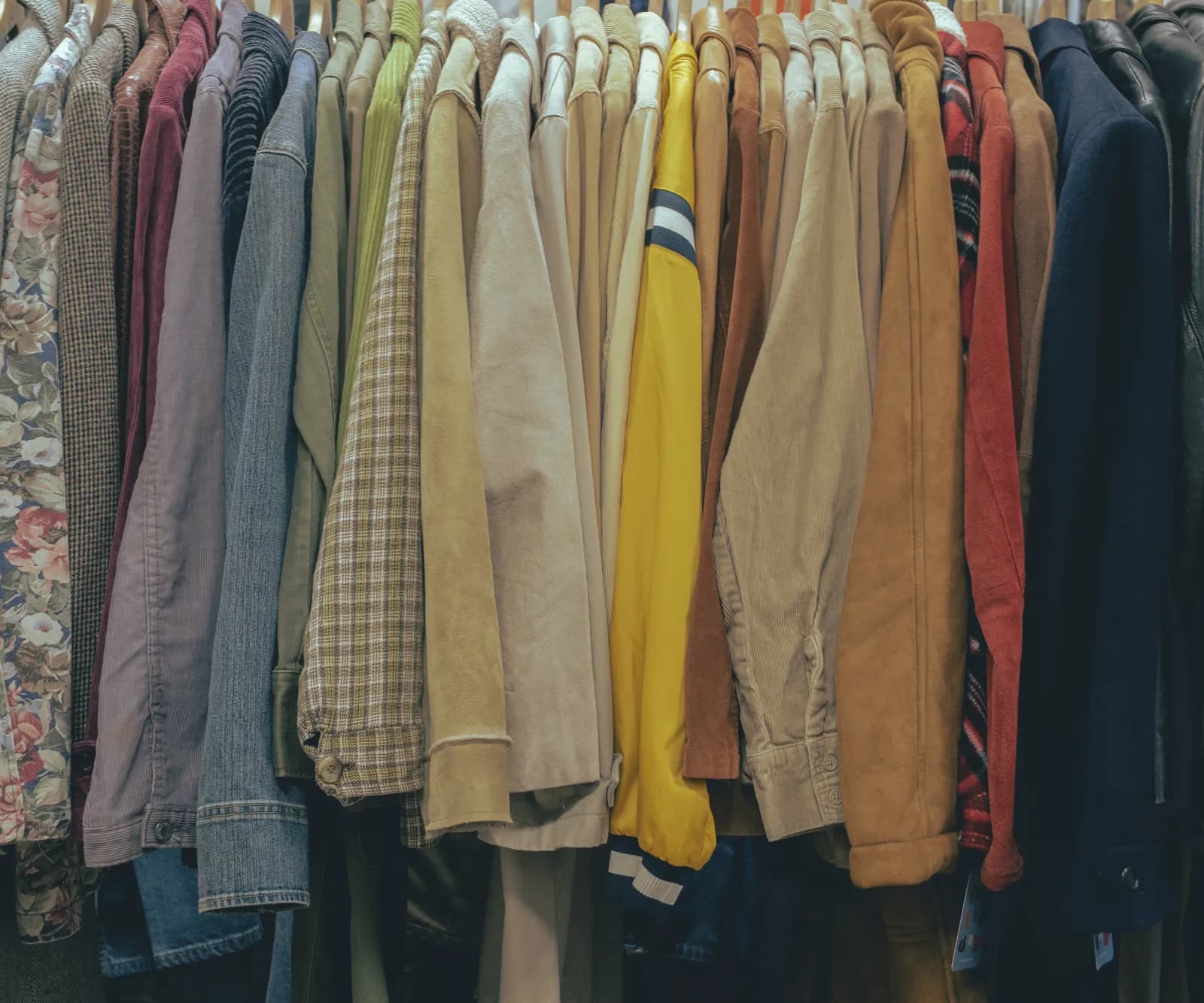 A packed rack of vintage jackets in corduroy, suede and denim